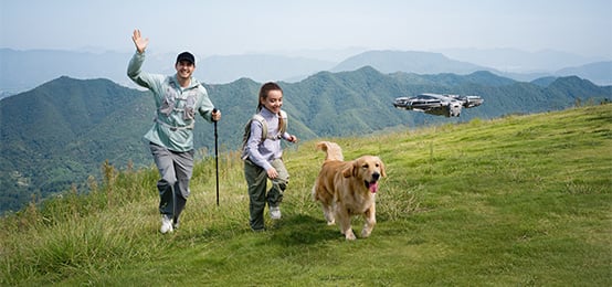 Dron nagrywający ojca z córką i psem na wycieczce w górach